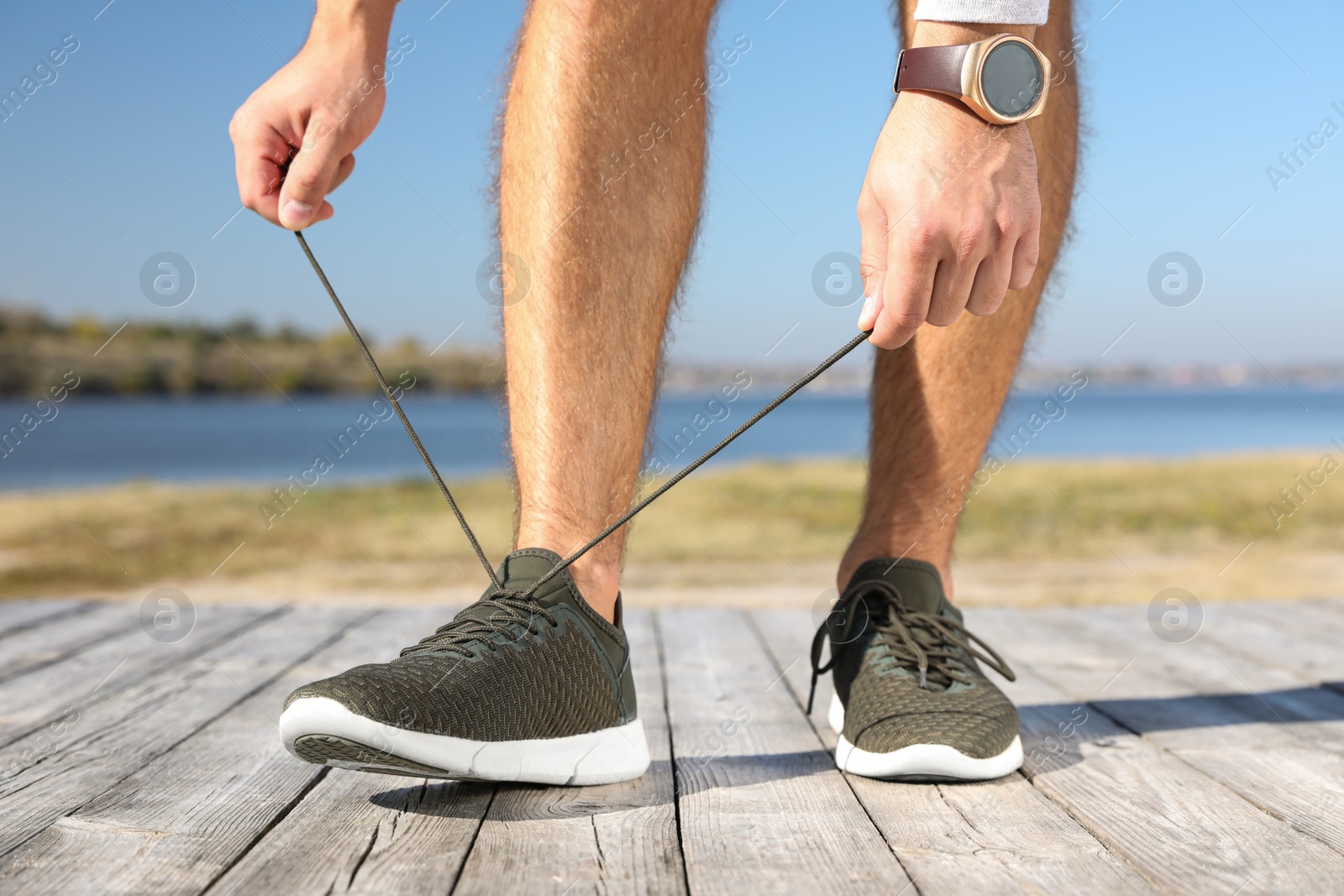 Photo of Sporty man tying shoelaces before running outdoors