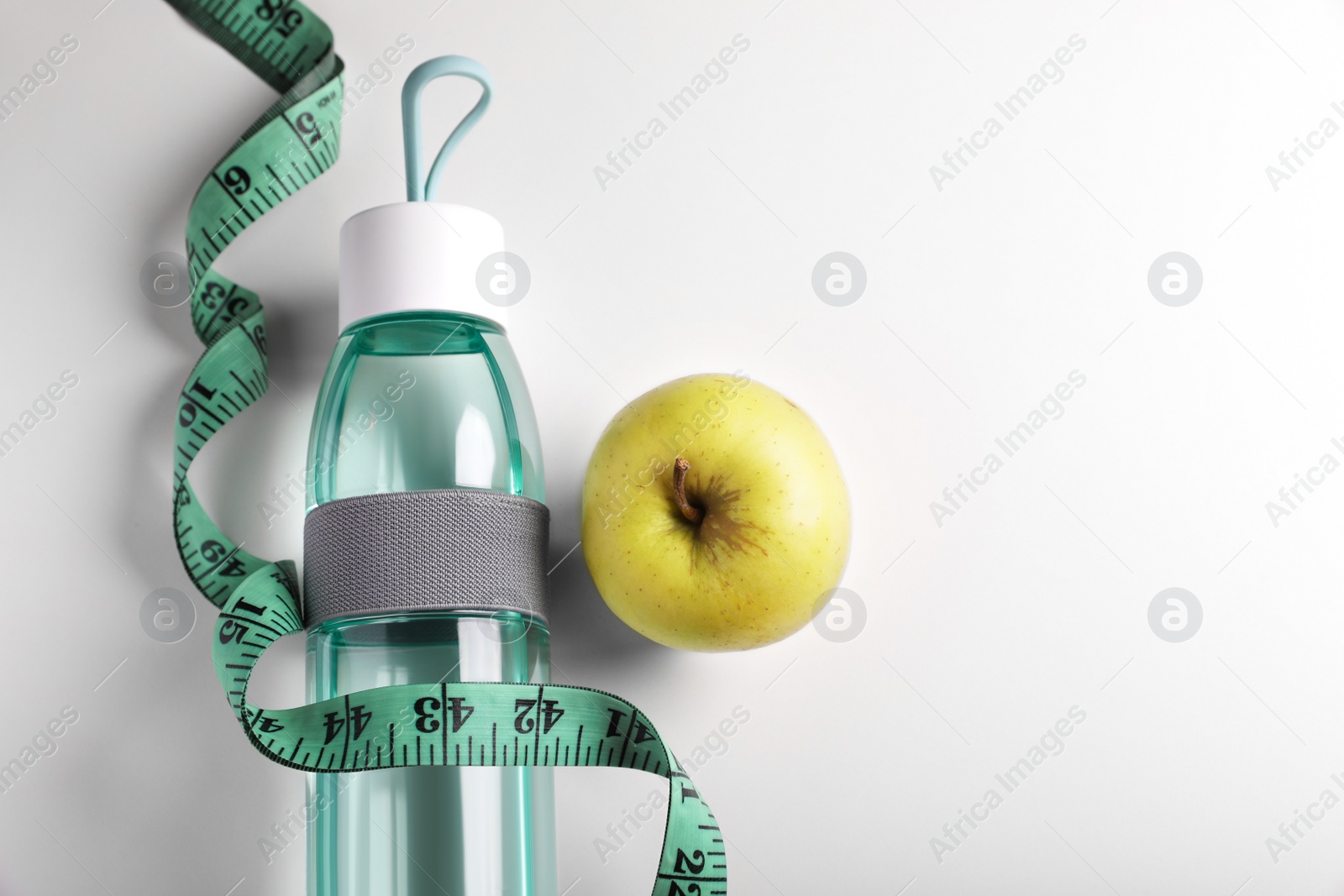 Photo of Measuring tape, apple and bottle of water on white background, flat lay with space for text. Weight control concept