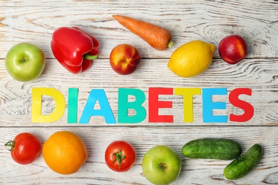 Flat lay composition with word "Diabetes", fruits and vegetables on wooden background