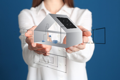 Image of Designer presenting project of house with solar panels on blue background