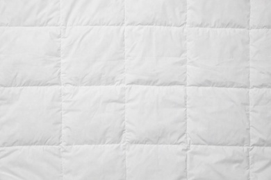 Photo of Soft quilted blanket as background, top view