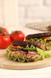 Delicious sandwiches with tuna and vegetables on white table