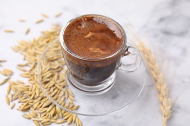 Cup of barley coffee, grains and spike on light table, closeup