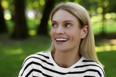 Portrait of happy woman in casual clothes outdoors. Beautiful lady with blonde hair at park