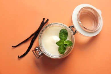 Jar with vanilla pudding, sticks and fresh mint on color background