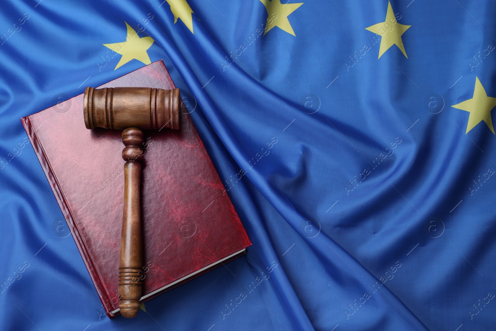 Photo of Wooden judge's gavel and book on flag of European Union, top view. Space for text
