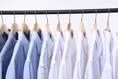 Photo of Dry-cleaning service. Many different clothes hanging on rack against white background, closeup