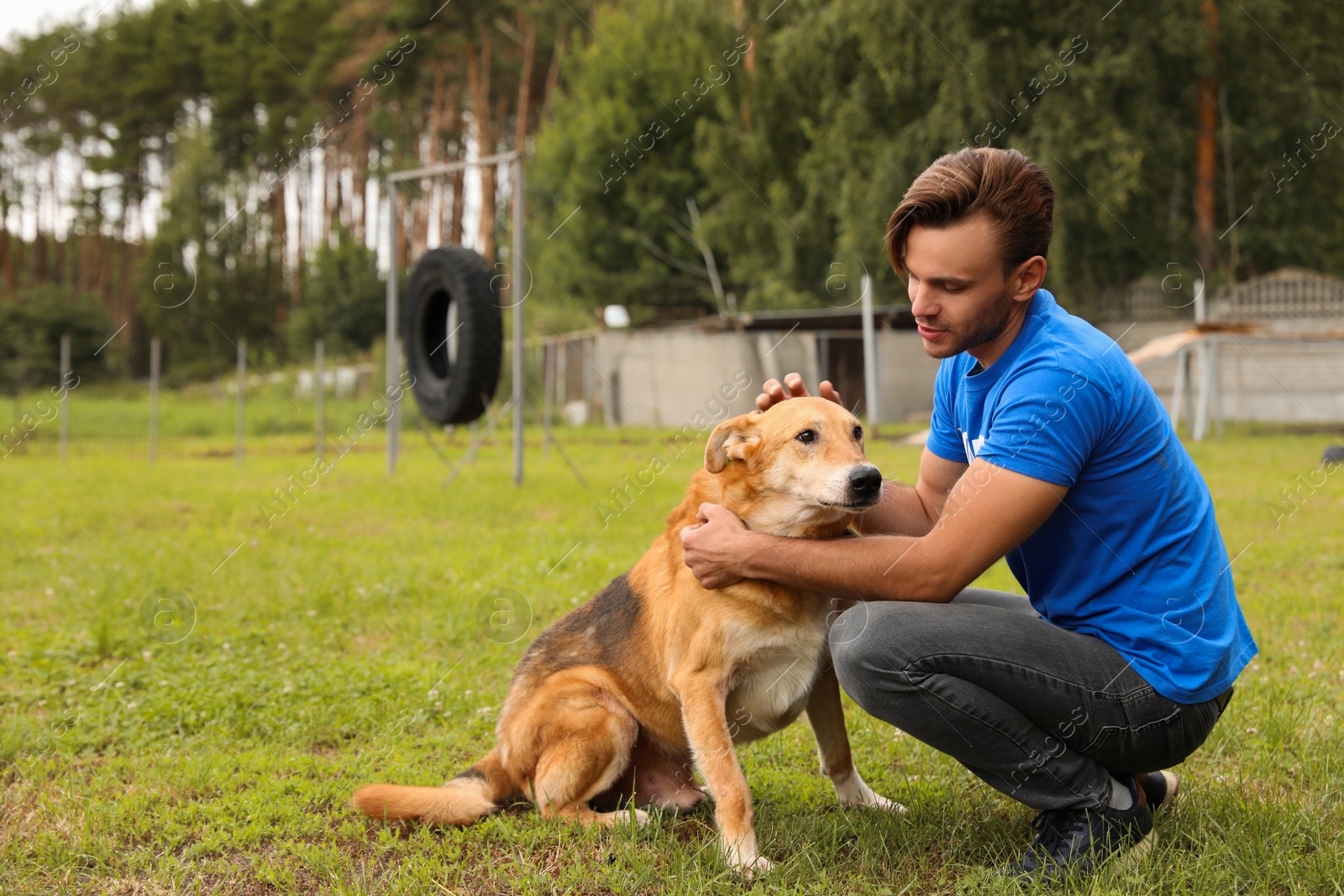 Photo of Male volunteer with homeless dog at animal shelter outdoors