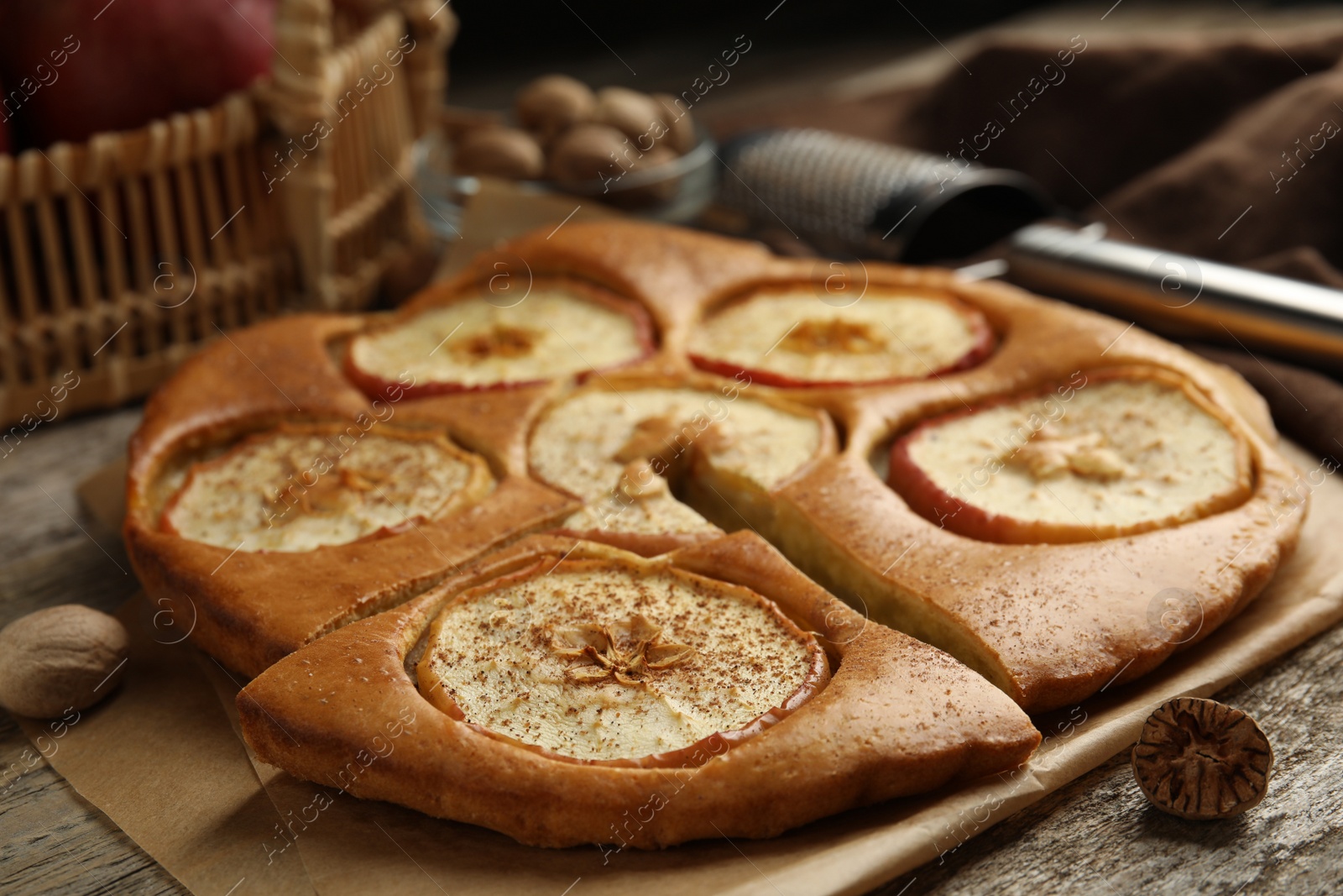 Photo of Tasty apple pie with nutmeg powder on wooden table, closeup