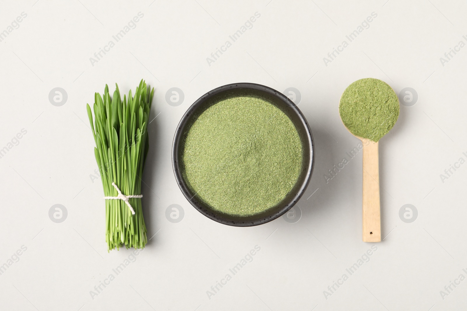 Photo of Wheat grass powder and fresh green sprouts on light table, flat lay