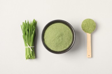 Wheat grass powder and fresh green sprouts on light table, flat lay