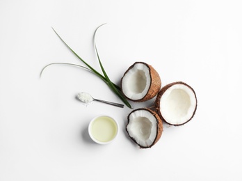 Photo of Bowl of natural organic oil and coconuts on white background, top view