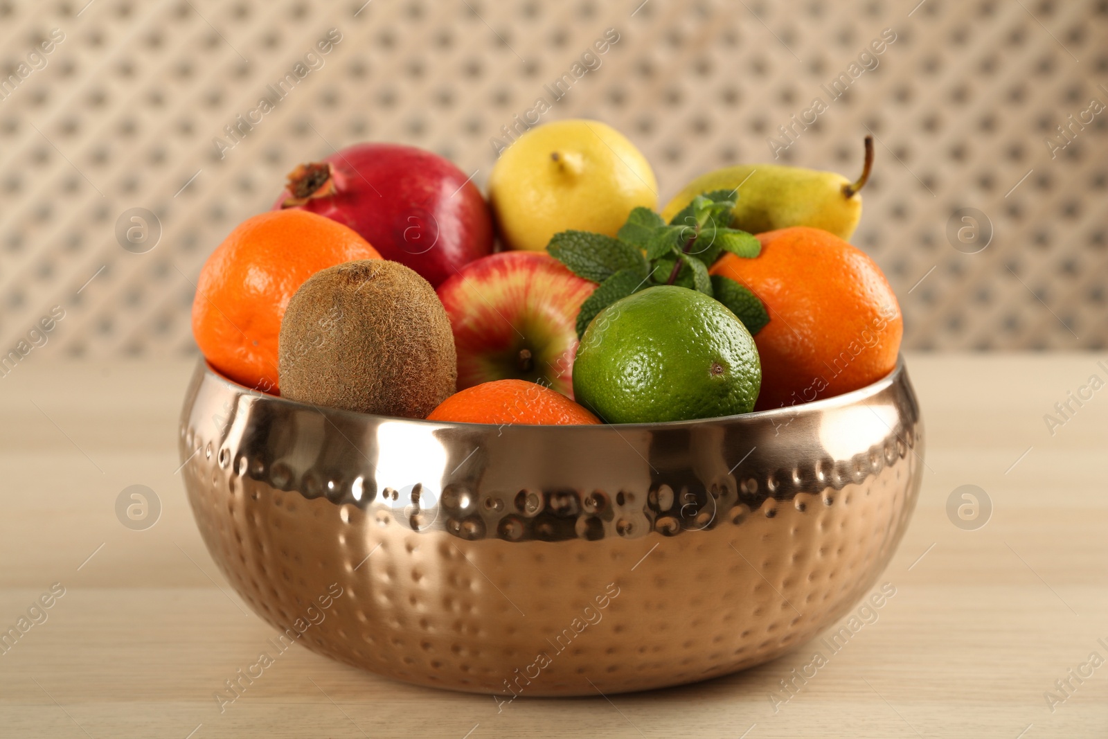 Photo of Fresh ripe fruits in metal bowl on wooden table, closeup