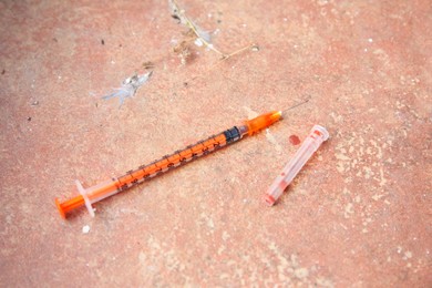 Disposable syringe with needle on red tiled surface