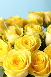 Beautiful bouquet of yellow roses on light blue background, closeup