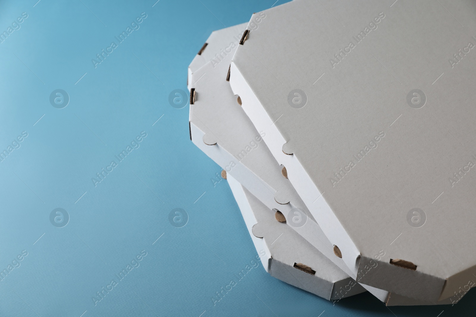 Photo of Stack of empty pizza boxes on light blue background, closeup. Space for text