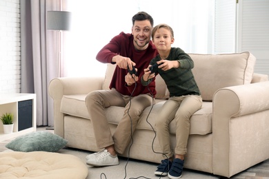 Photo of Father and son playing video games at home
