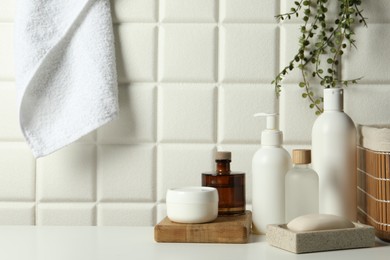 Different bath accessories and personal care products on white table near tiled wall