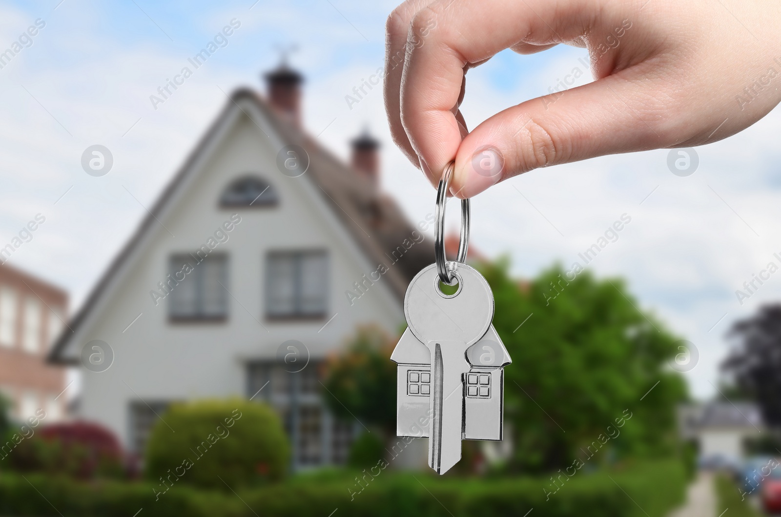 Image of Woman holding key near house outdoors, closeup