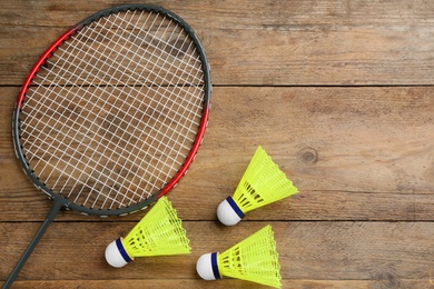 Photo of Racket and shuttlecocks on wooden table, flat lay with space for text. Badminton equipment
