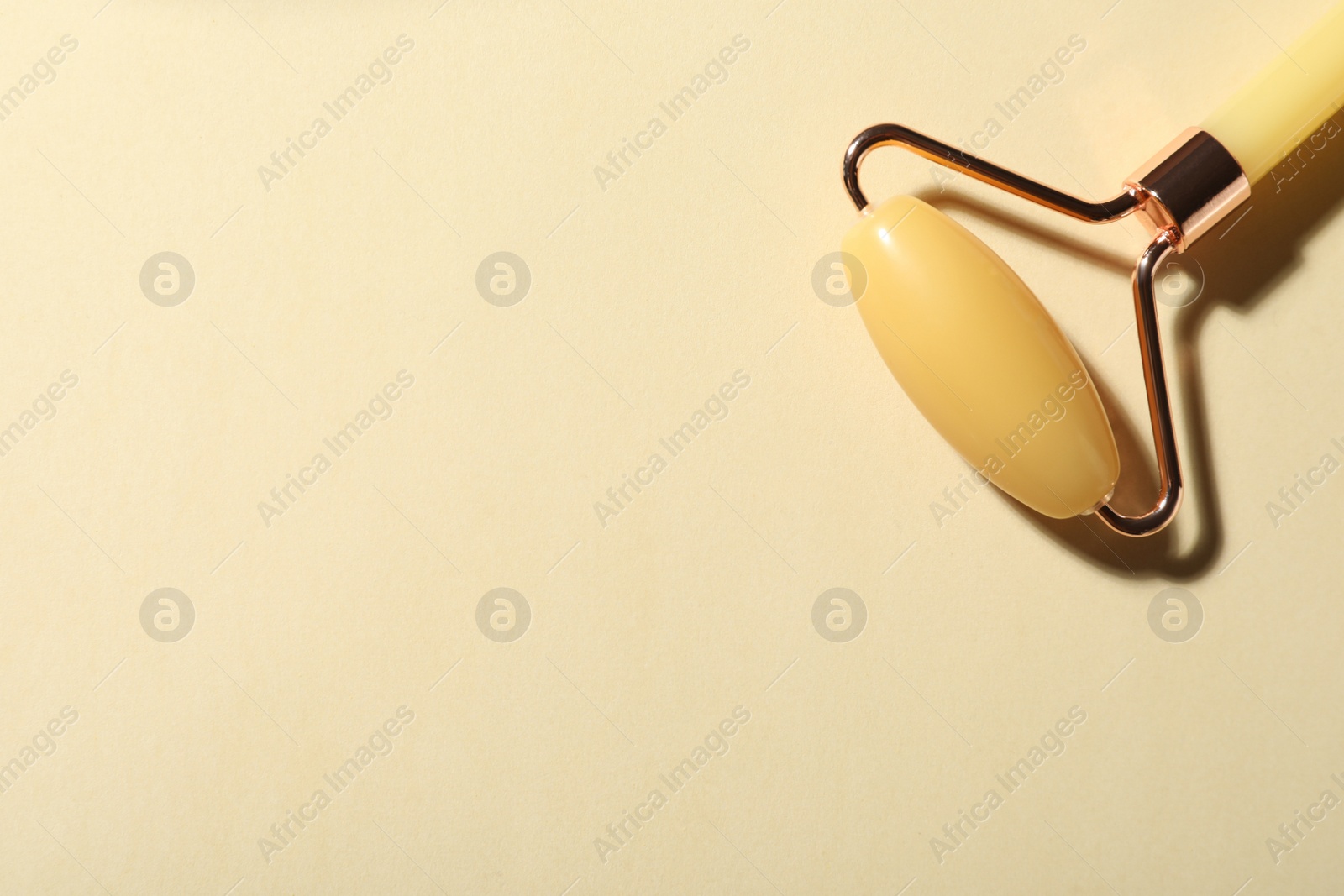 Photo of Natural jade face roller on beige background, top view. Space for text