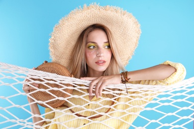 Beautiful young woman posing near net on color background. Summer fashion