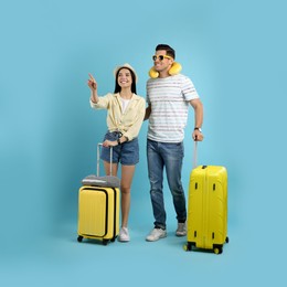 Photo of Couple of tourists with suitcases on light blue background