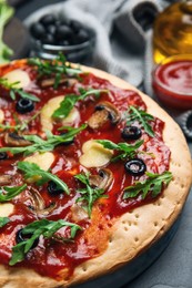 Photo of Pita pizza with cheese, olives, mushrooms and arugula on black table, closeup