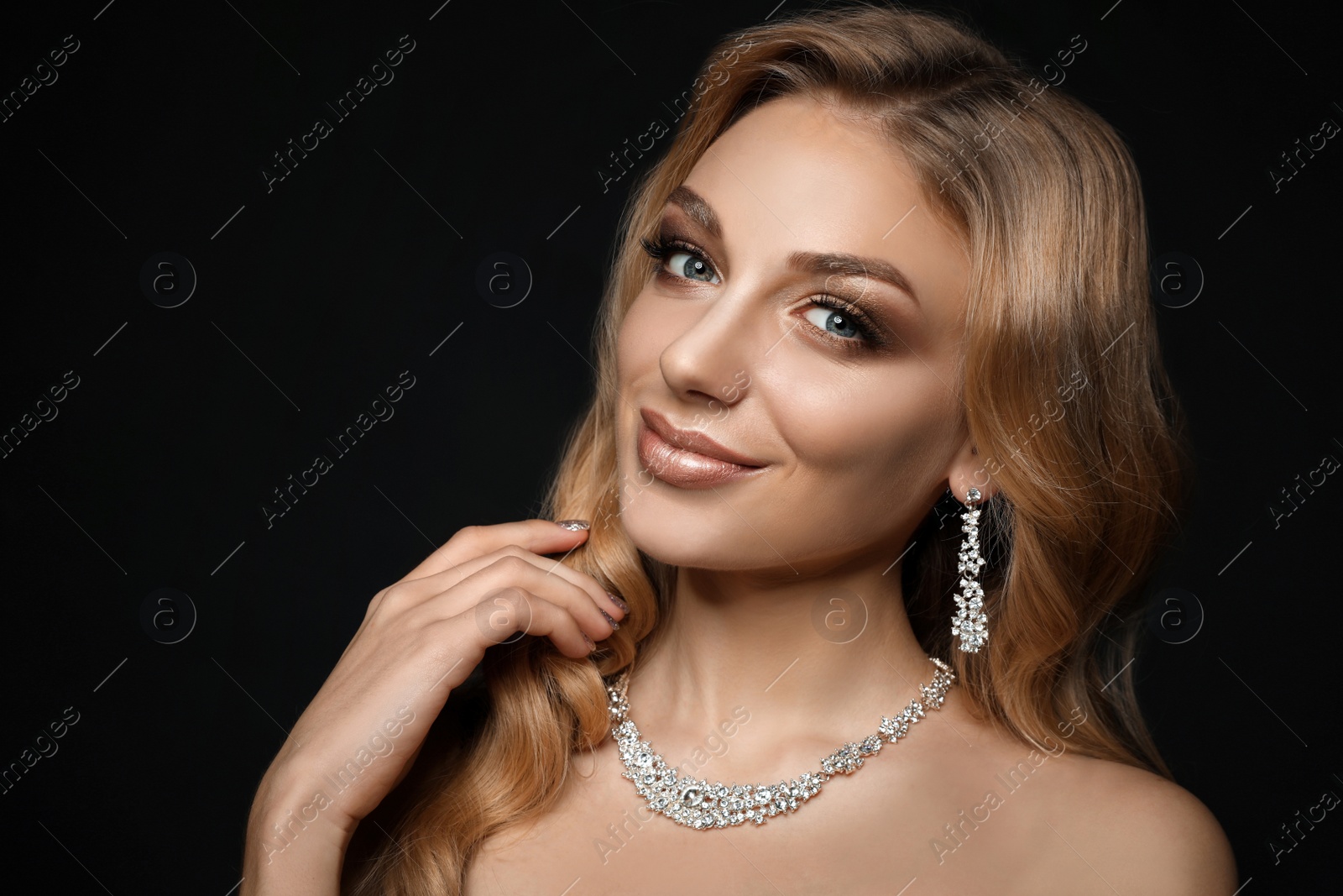 Photo of Beautiful young woman with elegant jewelry on dark background. Space for text