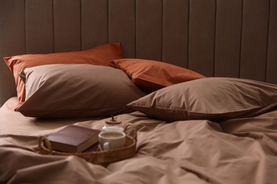 Cup of hot coffee and books on bed with stylish linens