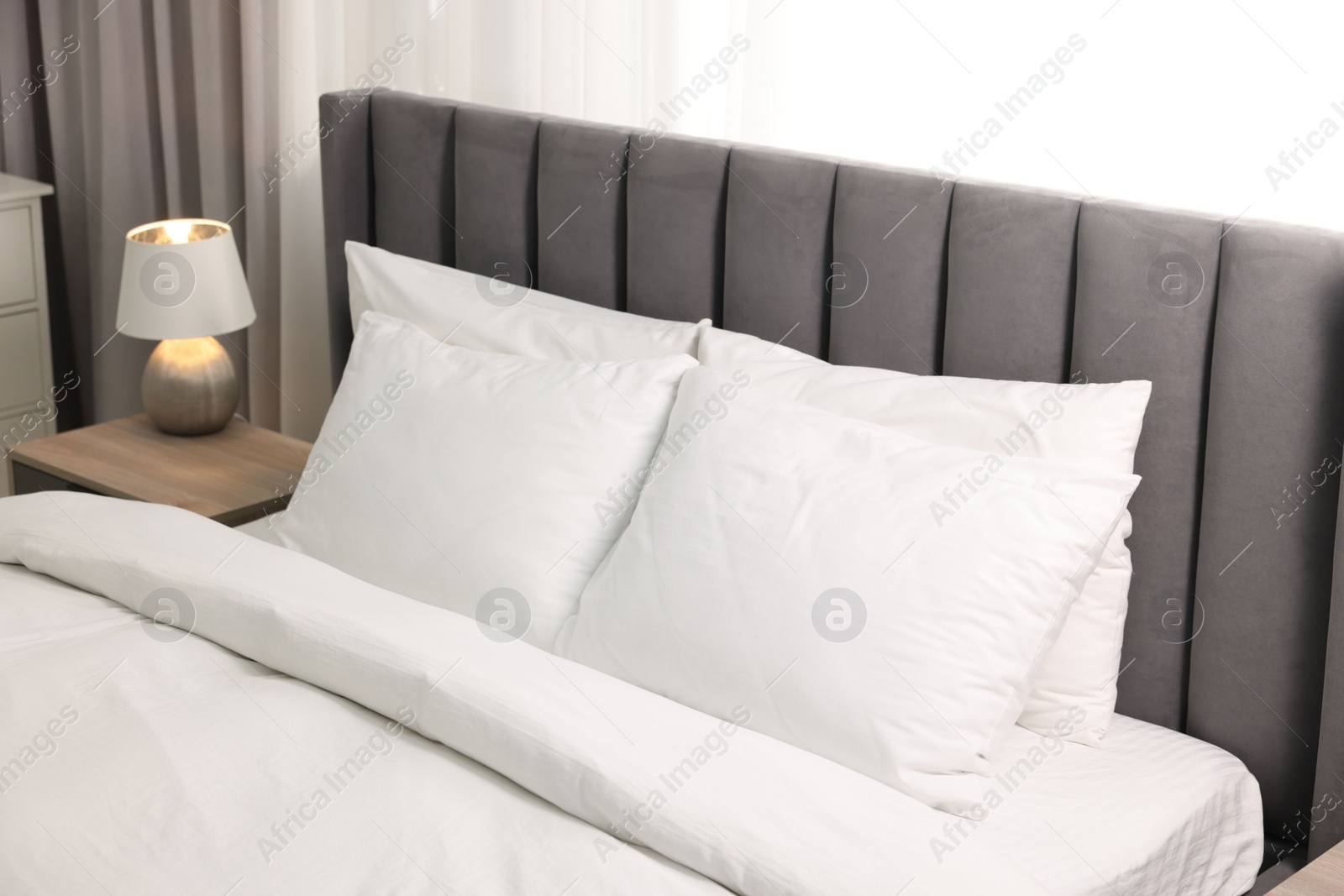 Photo of Soft white pillows and duvet on bed at home