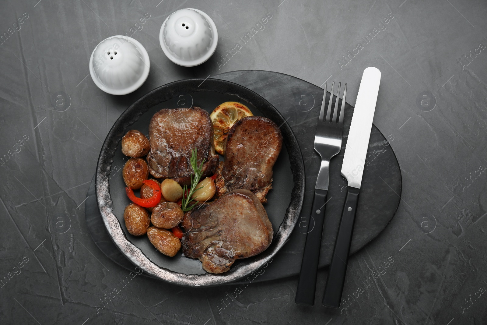 Photo of Tasty beef tongue pieces, rosemary, lemon and potatoes on grey table, flat lay