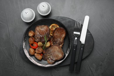 Tasty beef tongue pieces, rosemary, lemon and potatoes on grey table, flat lay