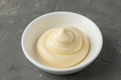 Fresh mayonnaise sauce in bowl on grey table, closeup