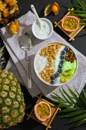 Tasty smoothie bowl with fresh kiwi fruit, blueberries and oatmeal served on black table, flat lay