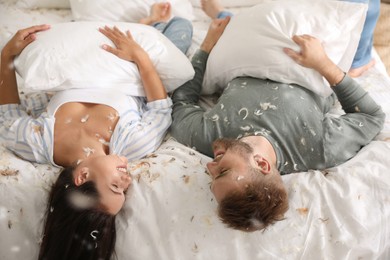 Happy young couple resting after fun pillow fight in bedroom