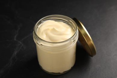 Jar of delicious mayonnaise and lid on black table