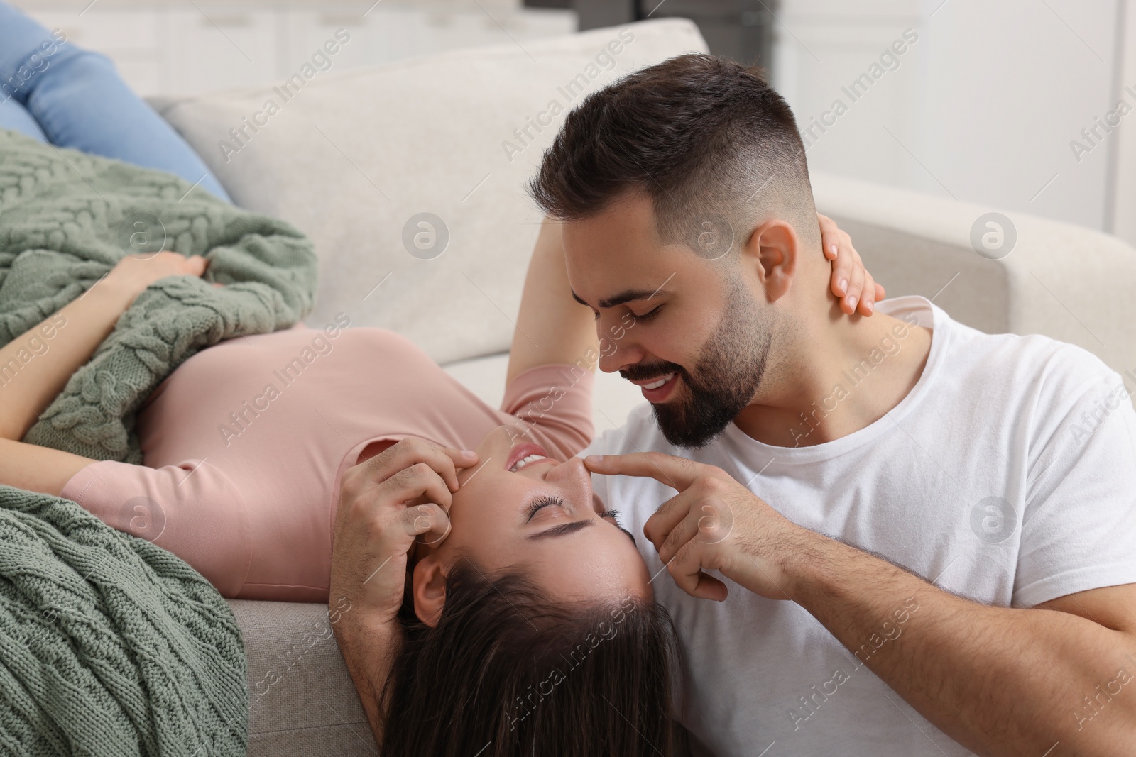 Photo of Affectionate young couple spending time together on sofa indoors