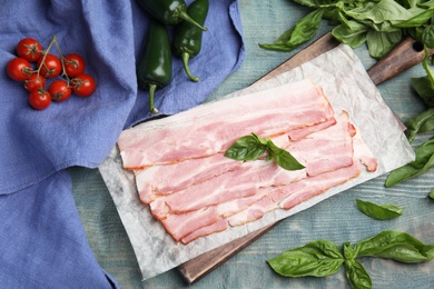 Photo of Flat lay composition with sliced raw bacon on light blue wooden table