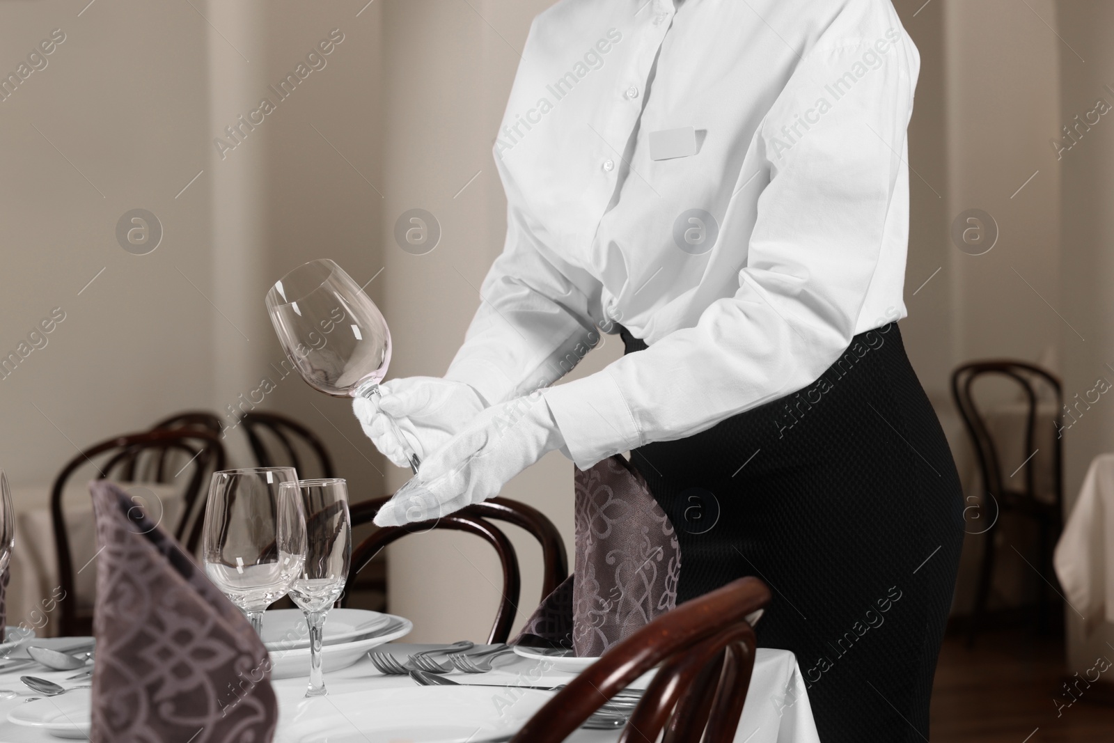 Photo of Woman setting table in restaurant, closeup. Professional butler courses