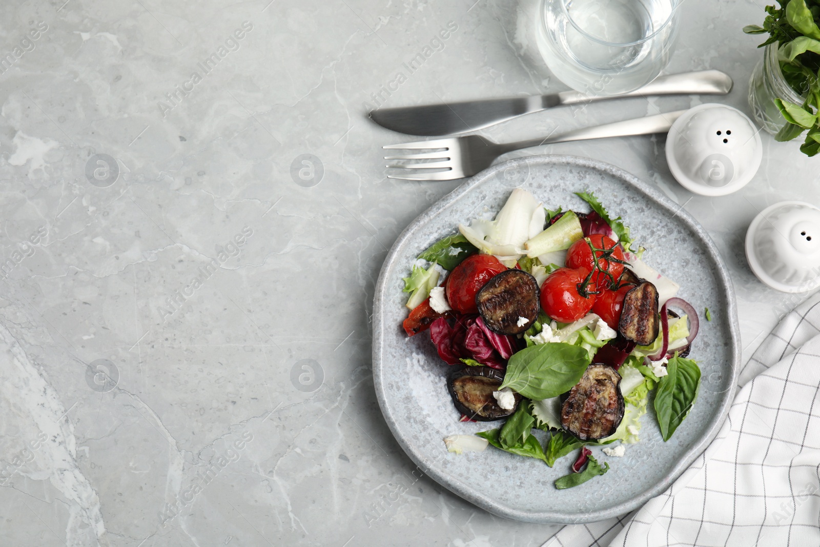 Photo of Delicious salad with roasted eggplant, basil and cheese served on grey marble table, flat lay. Space for text