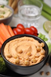 Plate with delicious hummus and fresh vegetables on white table, closeup