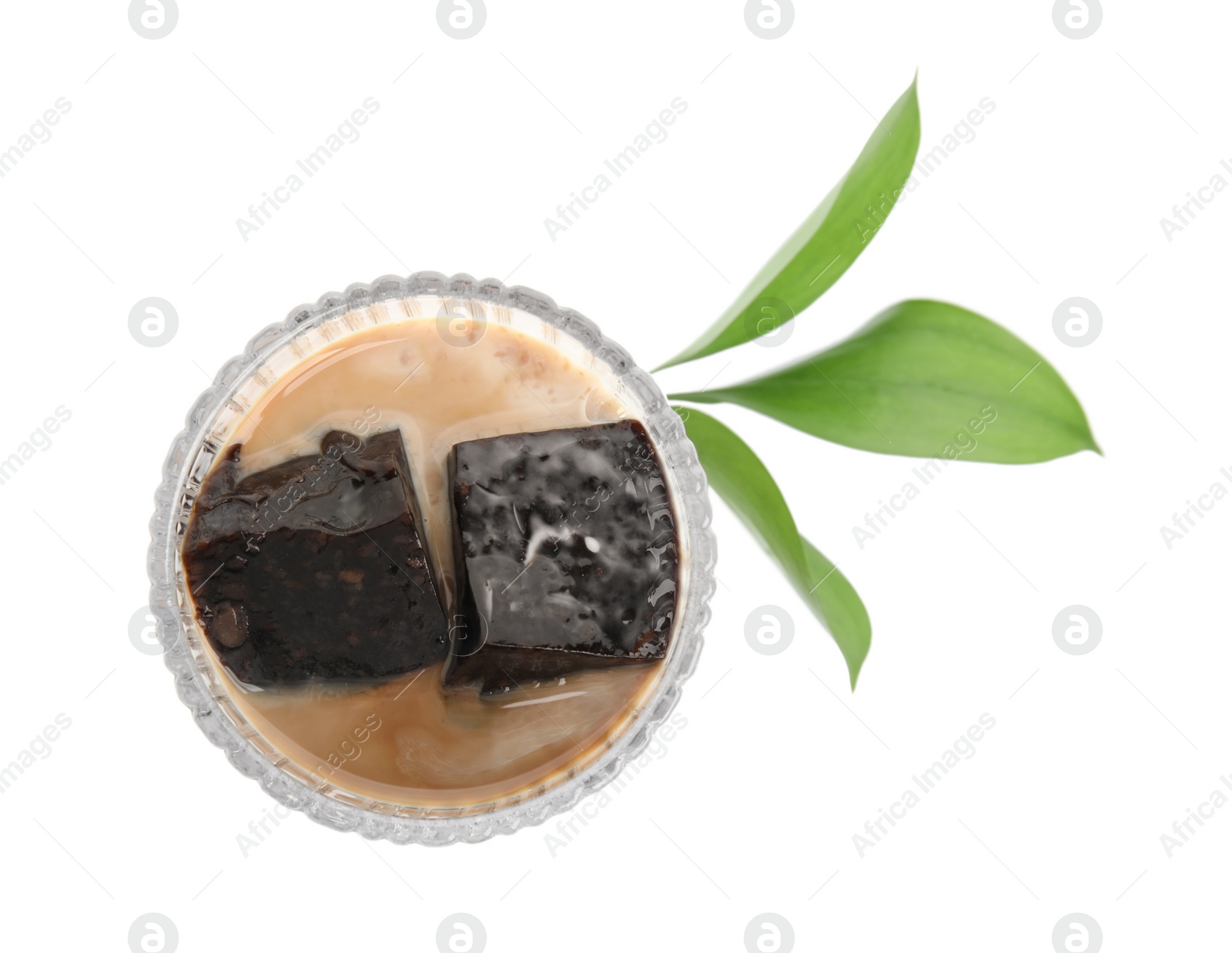 Photo of Glass of milk with grass jelly and green leaves on white background, top view