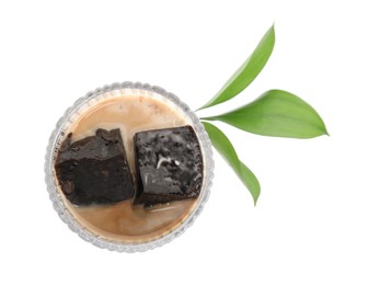 Photo of Glass of milk with grass jelly and green leaves on white background, top view