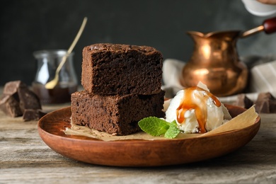 Plate with fresh brownies and ice-cream on table. Delicious chocolate pie