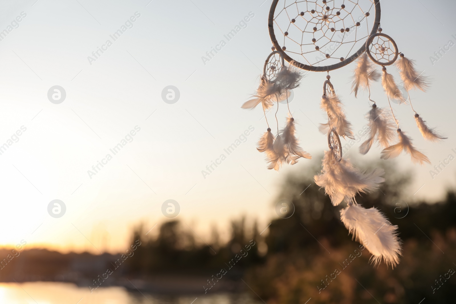 Photo of Beautiful handmade dream catcher near river on sunny day. Space for text