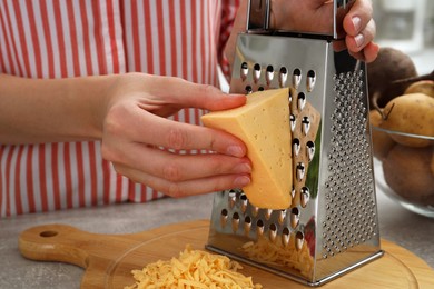 Photo of Woman grating cheese at kitchen table, closeup