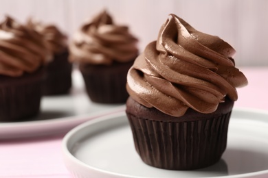 Photo of Delicious chocolate cupcake with cream on pink table, closeup