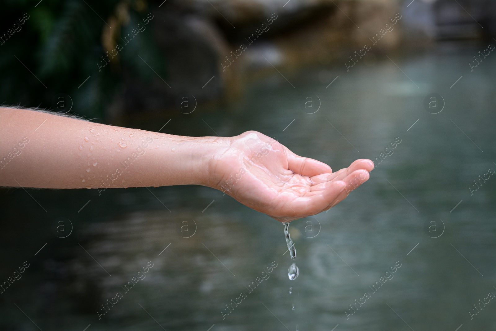 Photo of Kid pouring water from hand in pond, closeup