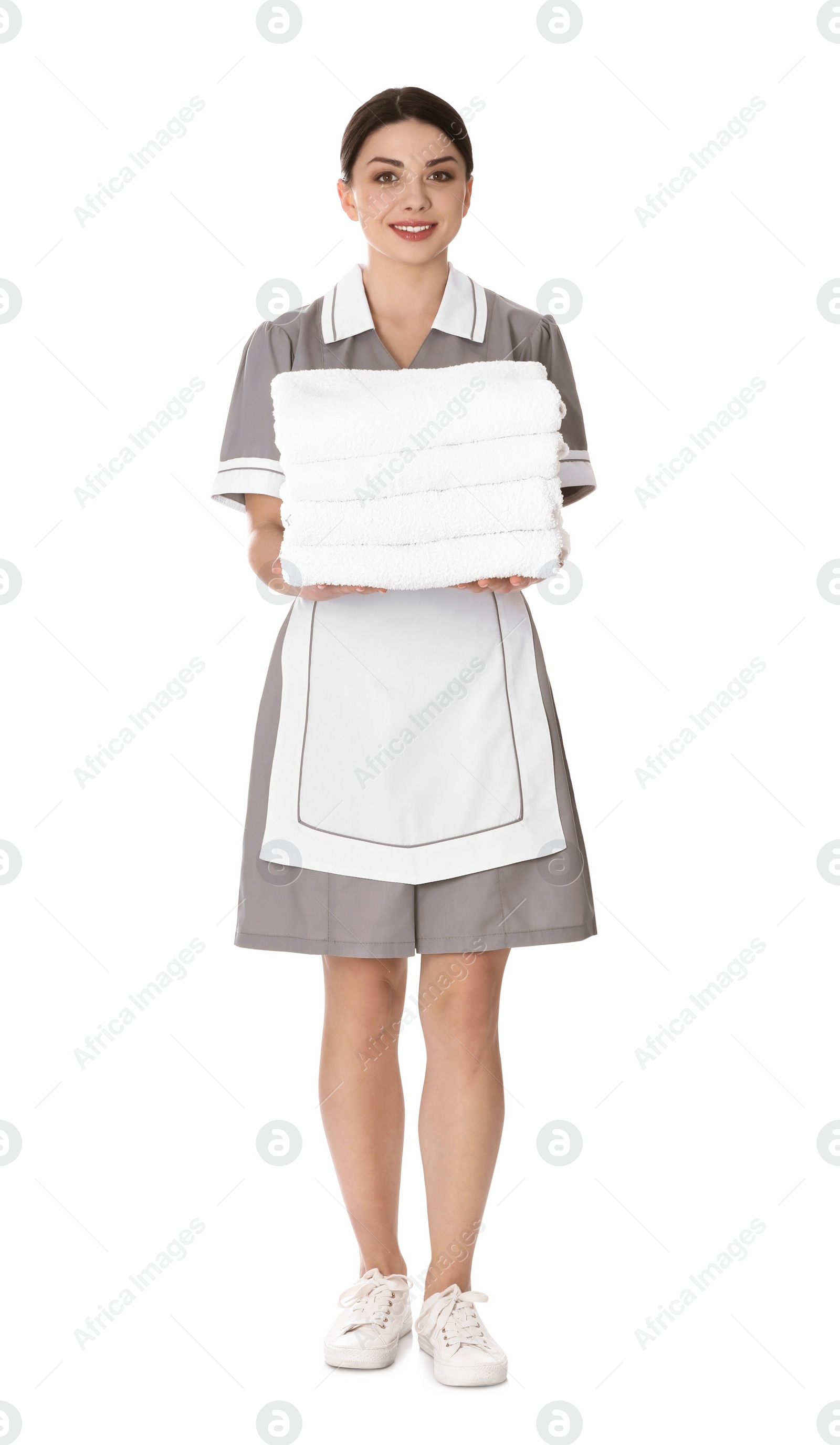 Photo of Young chambermaid holding stack of fresh towels on white background